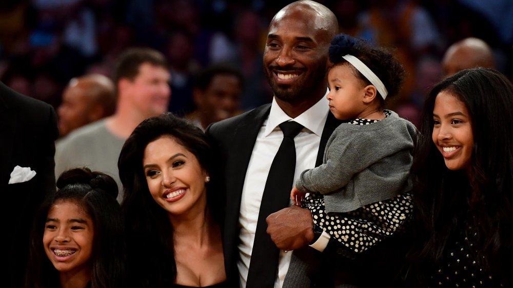 Kobe Bryant posa con su familia en el medio tiempo después de que sus camisetas # 8 y # 24 de Los Angeles Lakers se retiren