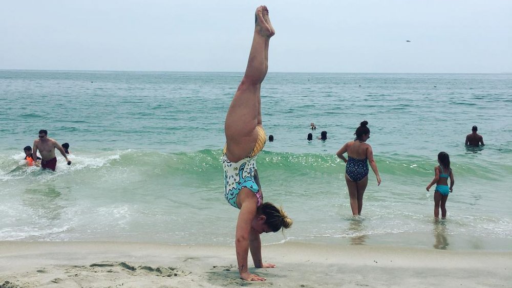 Victoria Caputo haciendo una parada de manos en la playa