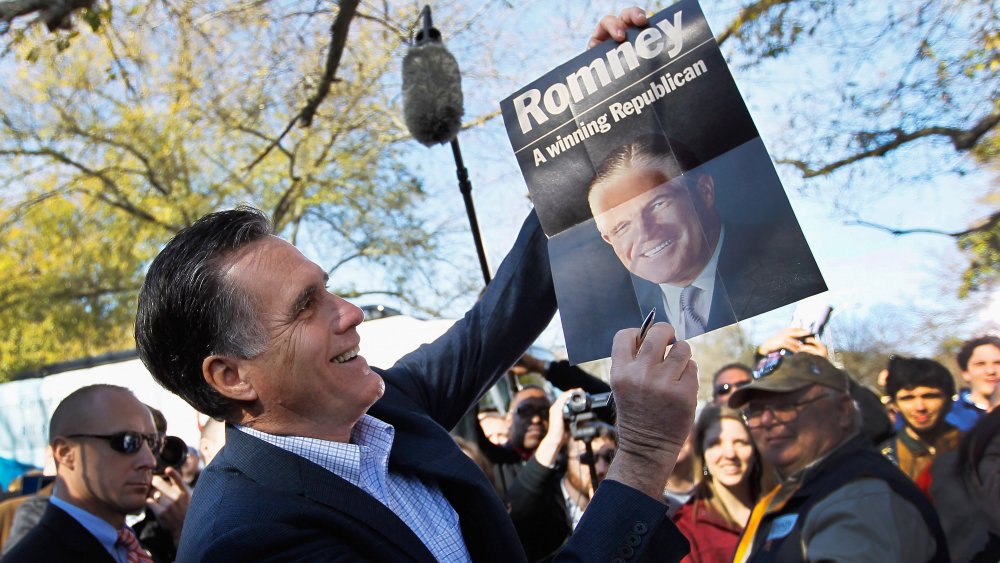 Mitt Romney sosteniendo un cartel de su padre, George Romney