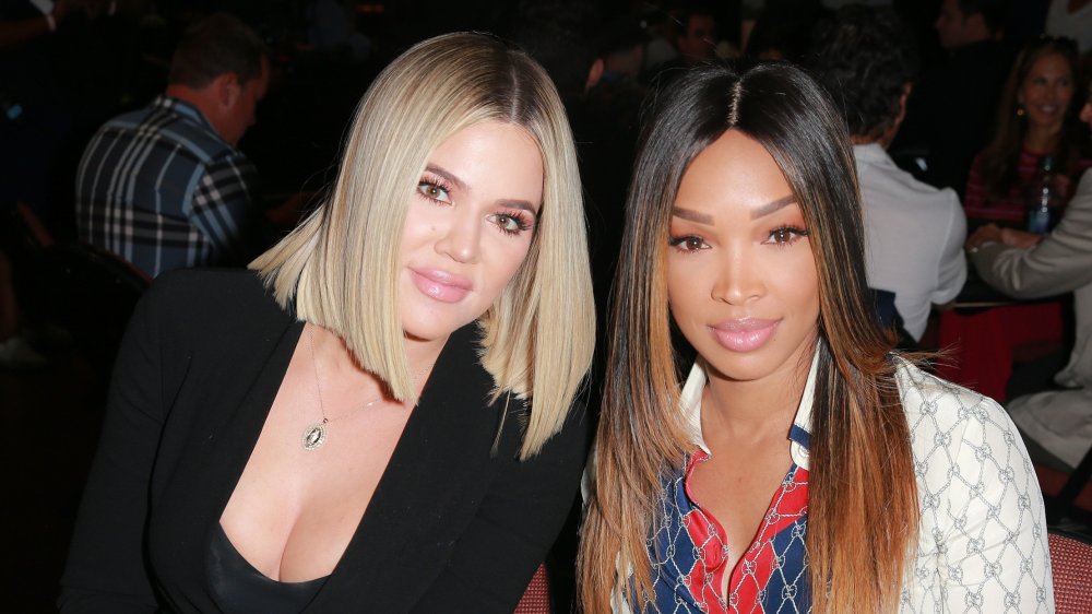 Khloe Kardashian y Malika Haqq sentadas y sonrientes en el evento