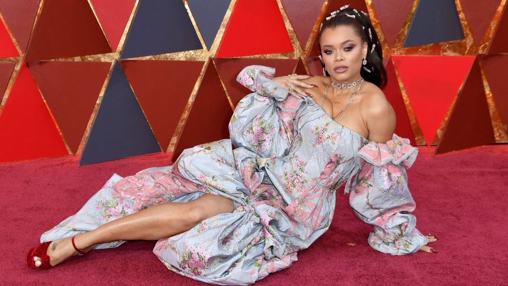 Andra Day haciendo una pose mientras se sienta en la alfombra roja