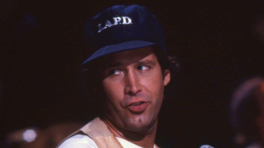 Chevy Chase hablando mientras mira a un lado y usa un sombrero