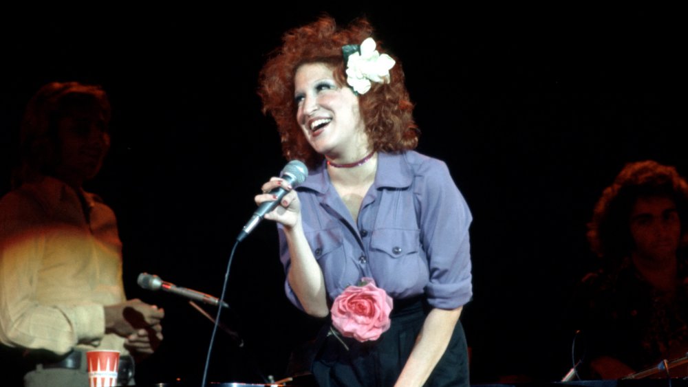 Bette Midler cantando con una flor en el pelo