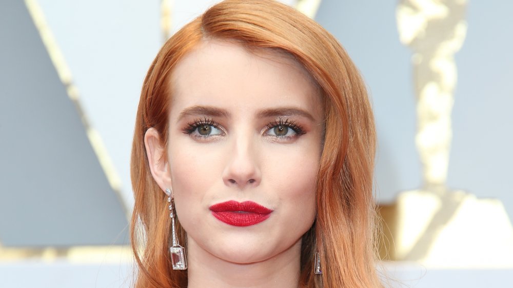 Emma Roberts posando en la alfombra roja con una expresión neutral