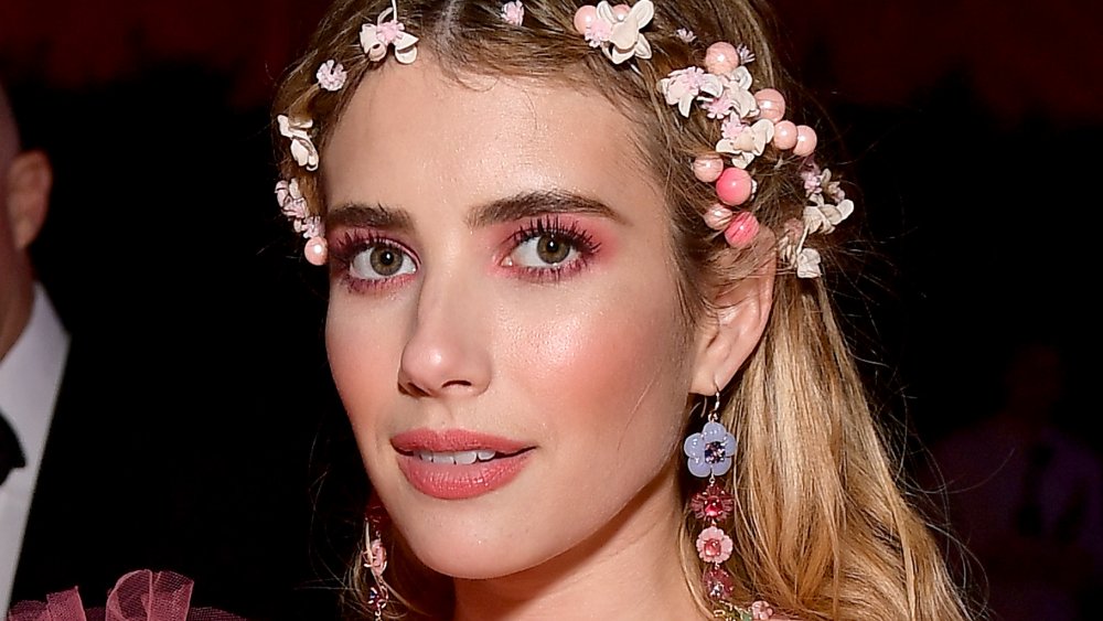 Emma Roberts mirando directamente a la cámara, con una corona de flores