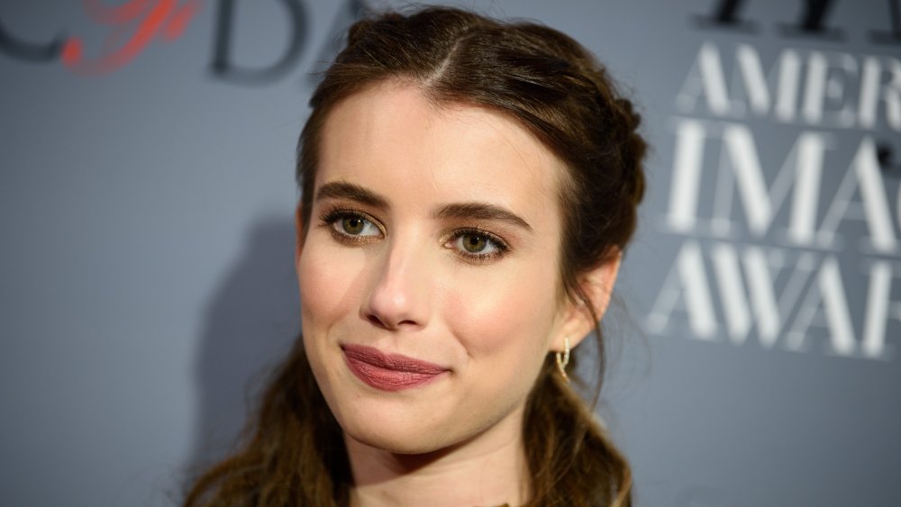 Emma Roberts mirando hacia un lado en la alfombra roja, sonriendo