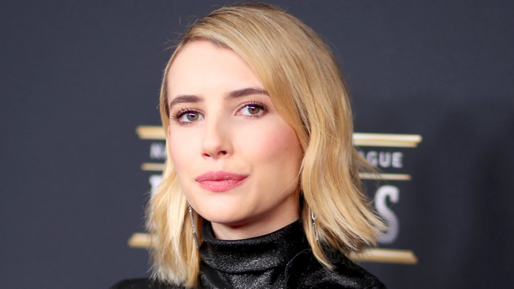 Emma Roberts posando en la alfombra roja con una expresión neutral