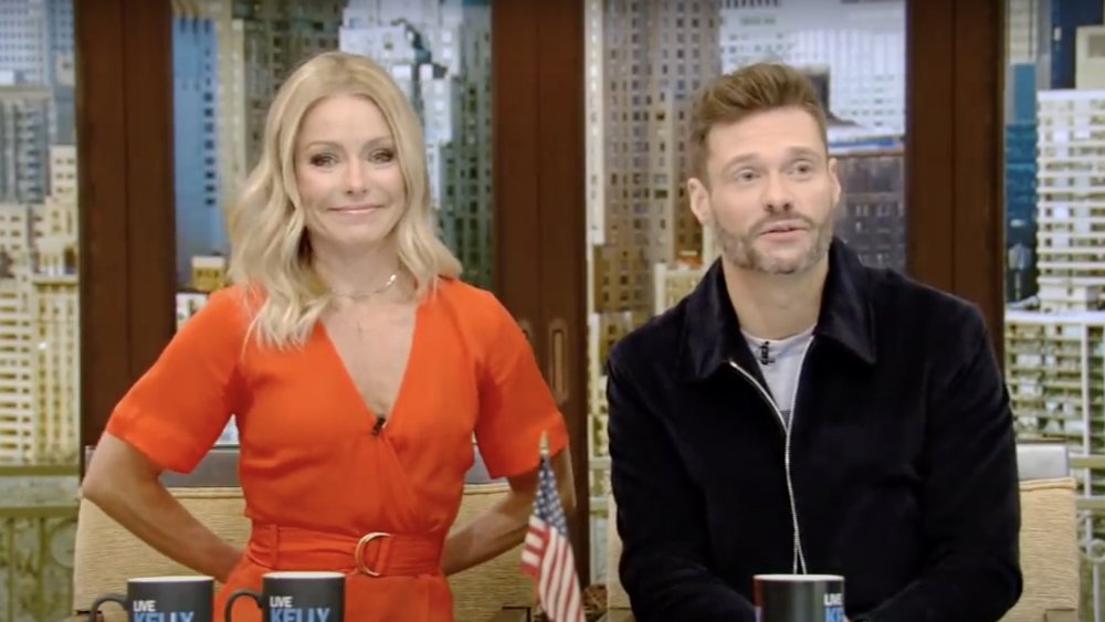 Kelly Ripa sonriendo con un vestido rojo junto a Ryan Seacrest