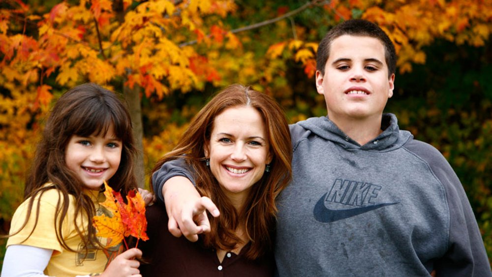 Ela Travolta, Kelly Preston y Jett Travolta abrazándose en una foto familiar