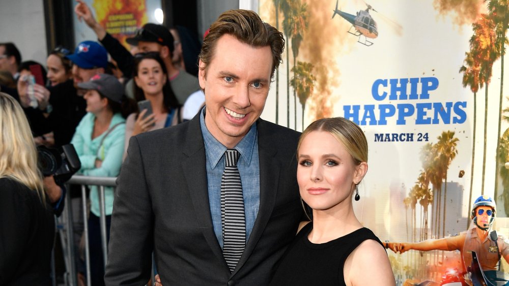 Dax Shepard sonriendo con el brazo alrededor de Kristen Bell