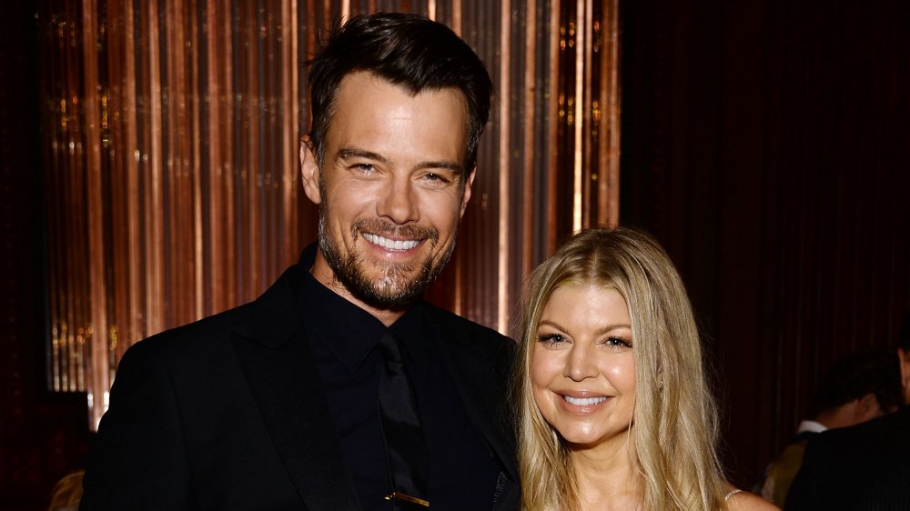 Josh Duhamel de pie junto a Fergie, ambos sonriendo