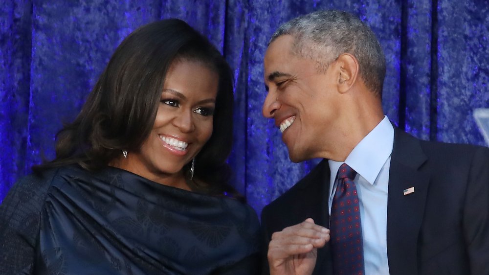 Michelle Obama riéndose mientras Barack Obama le sonríe