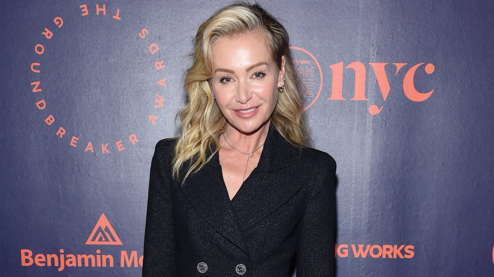 Portia de Rossi sonriendo con un vestido negro y brillante de gabardina