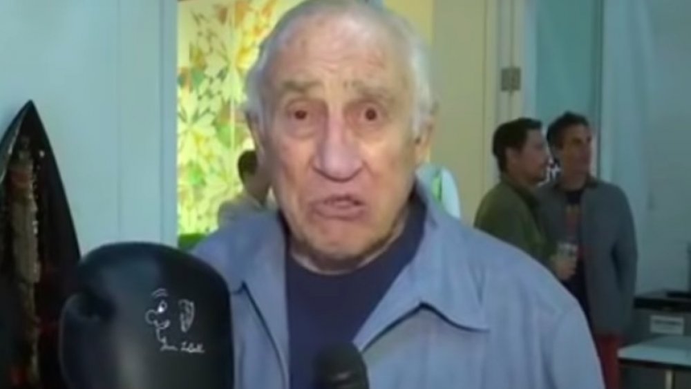 Gene LeBell sosteniendo un guante de boxeo durante una entrevista.