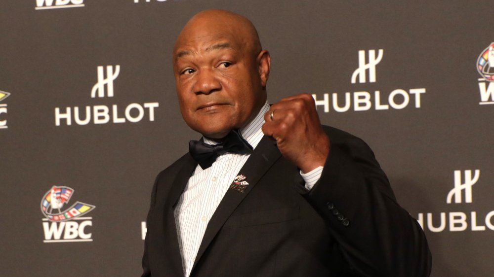 George Foreman con el puño en alto, vestido con un traje