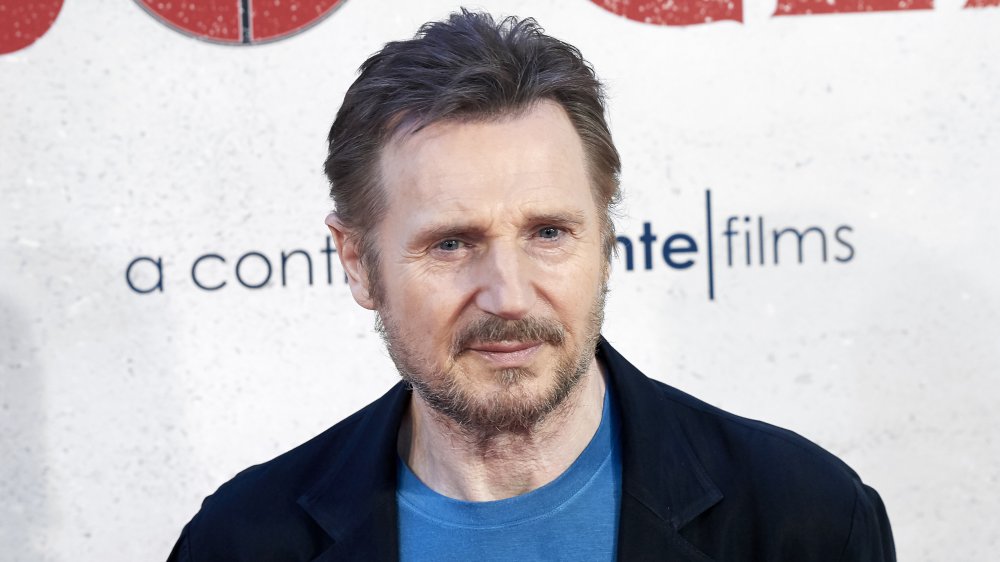 Liam Neeson posando con una expresión neutral en un traje azul