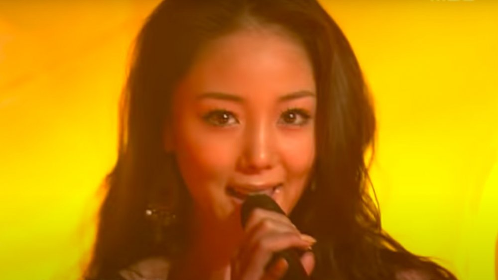 Lee Hye-ryeon (U-Nee) cantando sobre un fondo amarillo