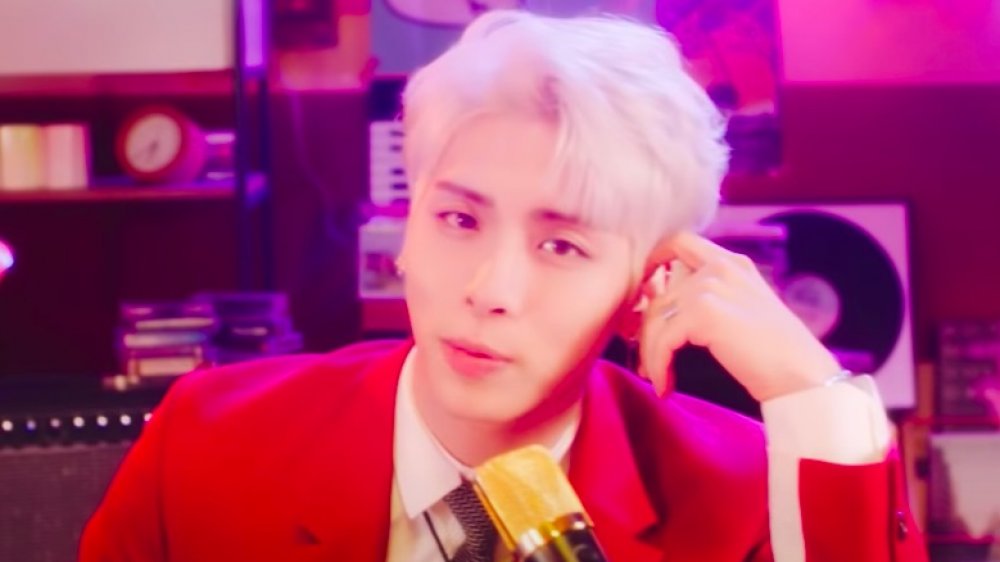 Jonghyun canta con un micrófono dorado y usa un traje rojo