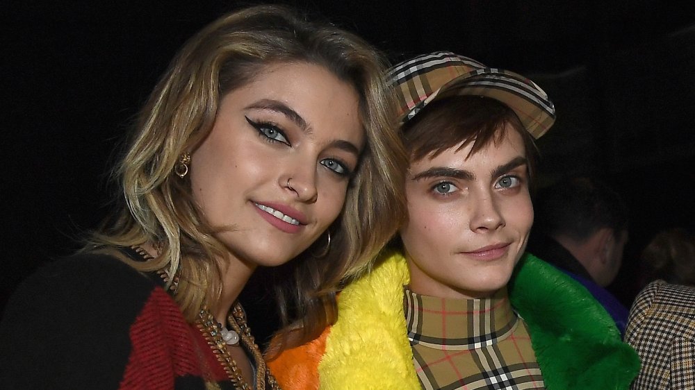 Paris Jackson y Cara Delevingne sonriendo a la cámara, apoyando la cabeza una contra la otra