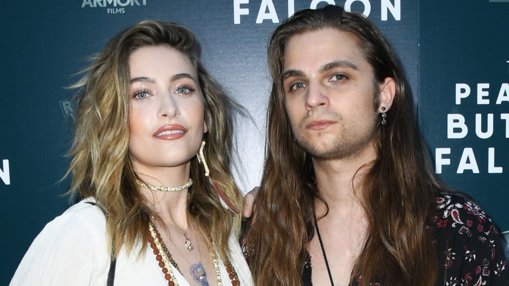 Paris Jackson con una camisa blanca y joyas de cuentas, sonriendo junto a su novio Gabriel Glenn