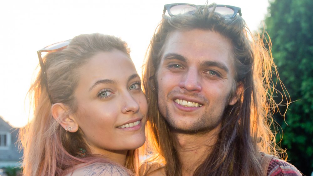 Paris Jackson y Gabriel Glenn sonriendo, mirando directamente a la cámara, en un evento externo