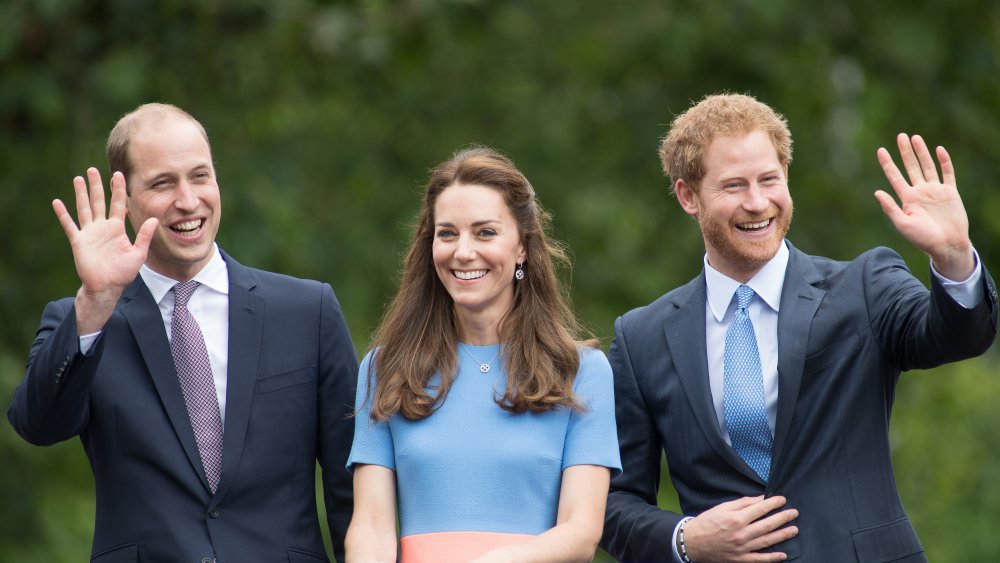 Príncipe William, Kate Middleton, Príncipe Harry sonriendo y saludando, todos vestidos de azul