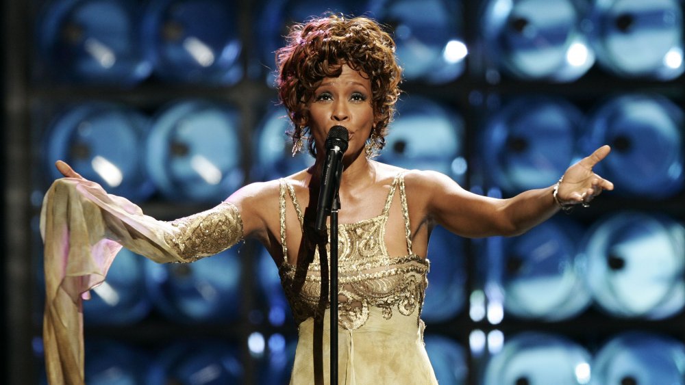 Whitney Houston cantando en vivo, con un vestido dorado