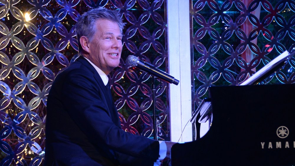 David Foster sonriendo mientras canta y toca el piano