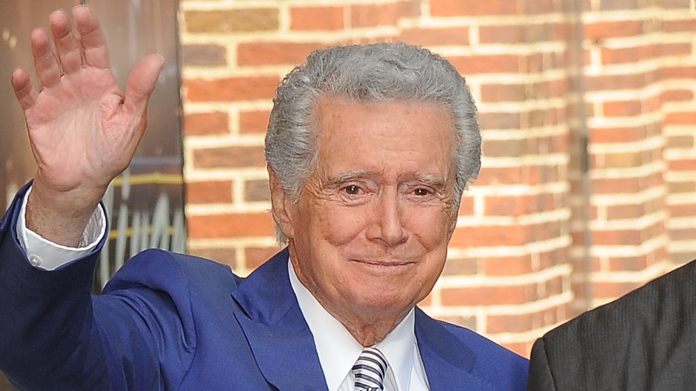 Regis Philbin en un traje azul, saludando, con una pequeña sonrisa.