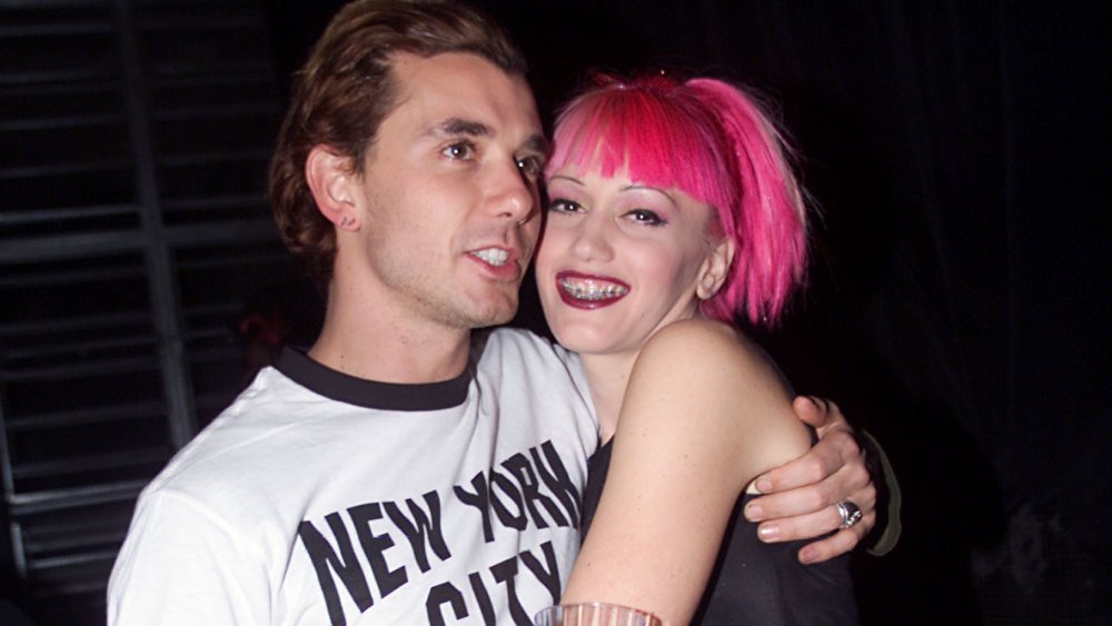 Gavin Rossdale con una camiseta blanca y negra, abrazando a una Gwen Stefani de cabello rosado en los años 90