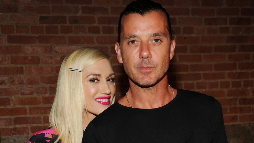 Gwen Stefani con un vestido rosa y negro, sonriendo detrás de Gavin Rossdale