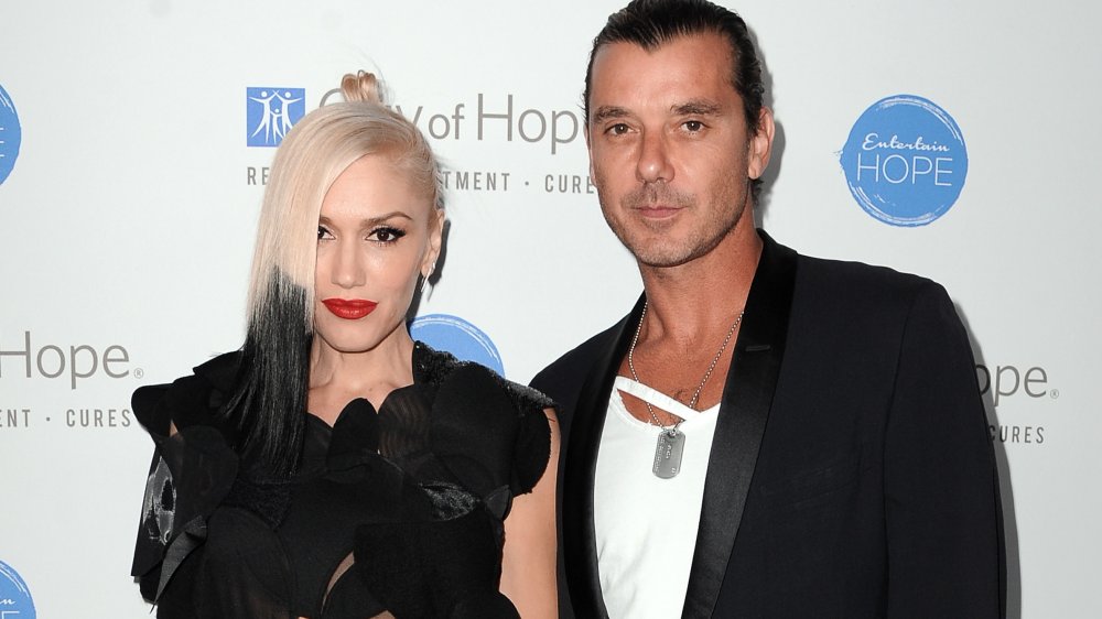 Gwen Stefani y Gavin Rossdale posando juntos con expresiones neutrales, ambas vestidas con trajes negros