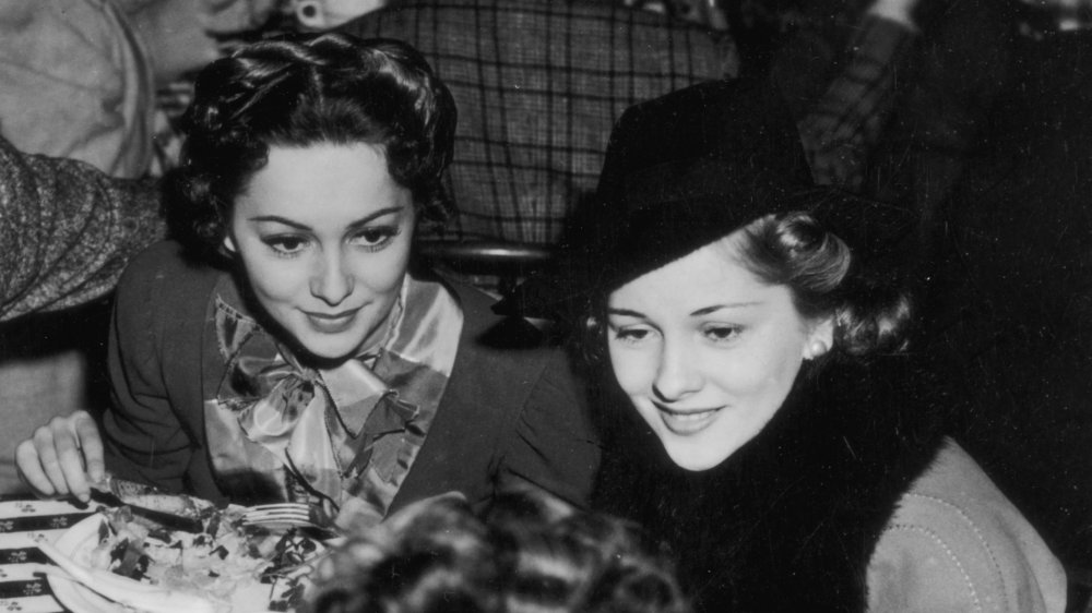 Olivia de Havilland y Joan Fontaine sentadas juntas en una cena en 1940