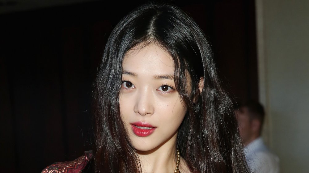 La fallecida estrella de K-pop Sulli posando en un evento con un vestido multicolor y un collar de oro