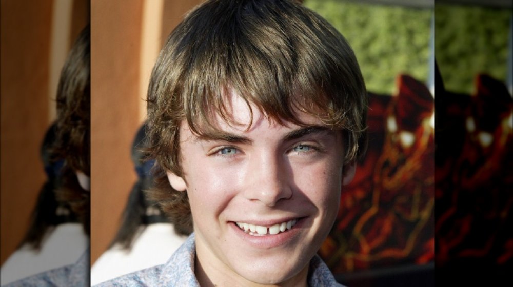 Zac Efron smiling at an event, showing off his old gap teeth