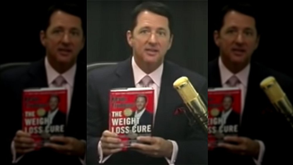 Kevin Trudeau sosteniendo una copia de su libro The Weight Loss Cure 