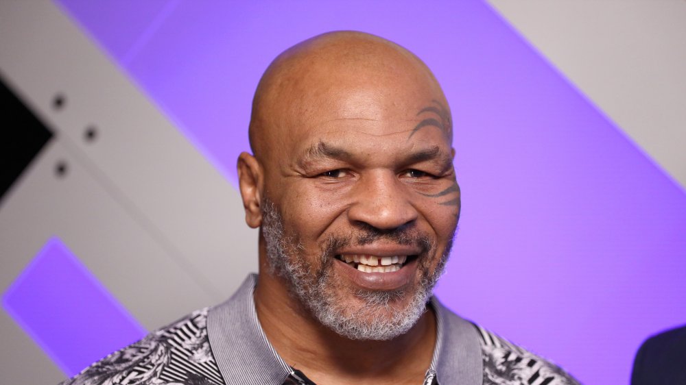 Mike Tyson sonriendo frente a la pared morada