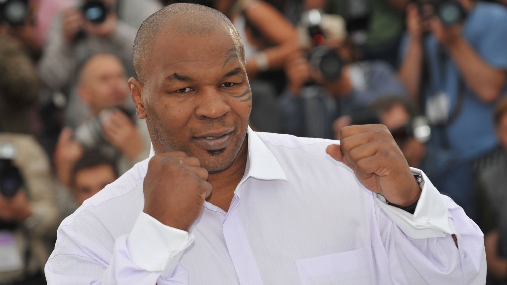 Mike Tyson con los puños en alto, posando en camisa blanca