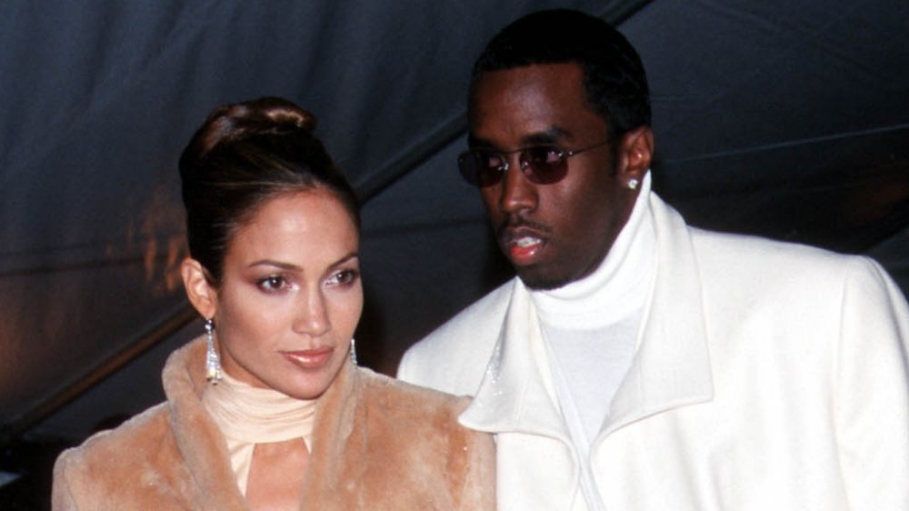 Jennifer Lopez con un abrigo de piel beige, Sean Combs con un chaquetón blanco, de pie en un evento de Met Gala en 1999