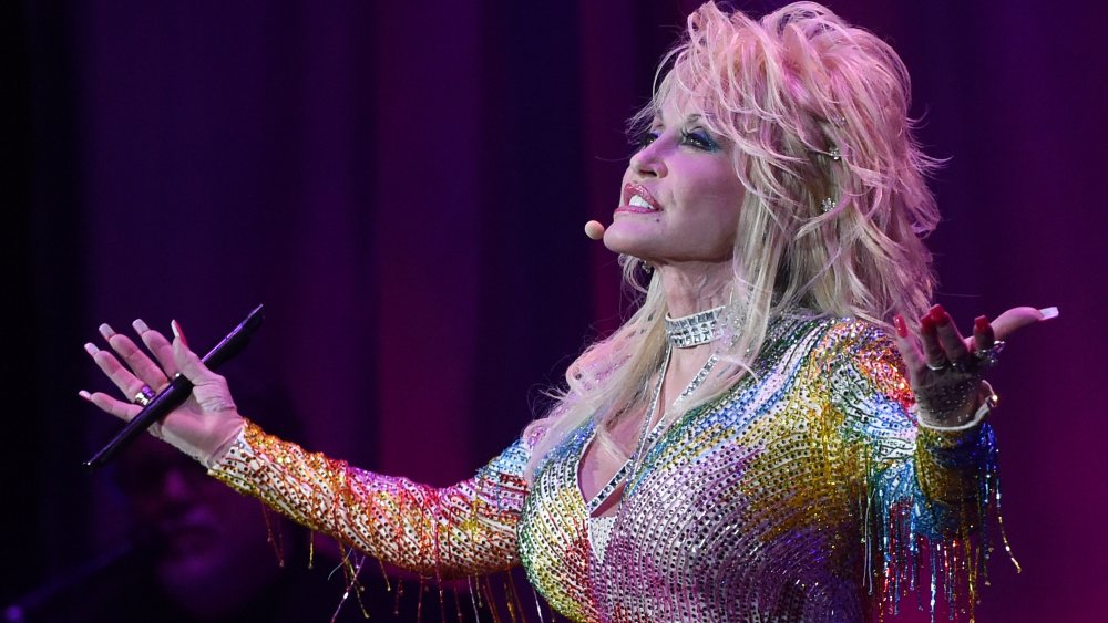 Dolly Parton cantando con un vestido brillante de colores del arco iris en 2015 a los 69 años