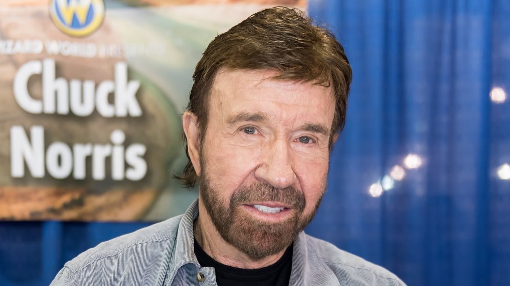 Chuck Norris sonriendo frente al cartel de Chuck Norris