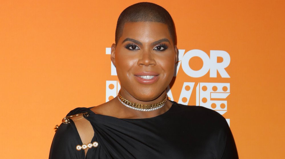 EJ Johnson con traje negro y gargantillas doradas y plateadas