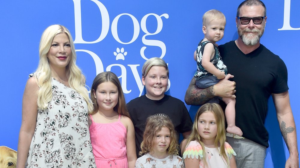 Tori Spelling con un vestido floral blanco, Dean McDermott con una camiseta negra, posando con sus hijos