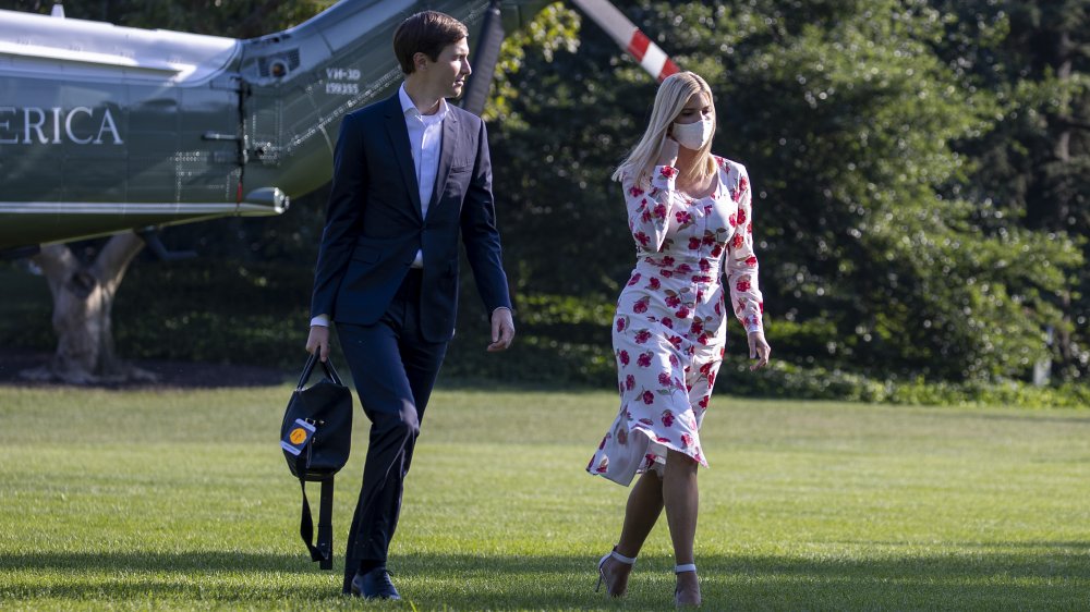 Jared Kushner en traje azul, Ivanka Trump con un vestido floral blanco y máscara facial, caminando fuera