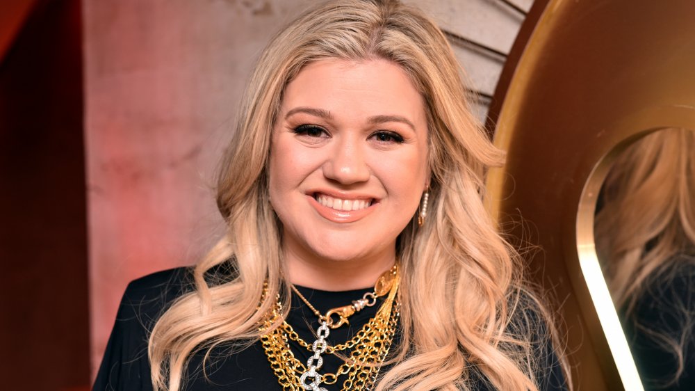 Kelly Clarkson con un vestido negro y joyas de oro, sonriendo