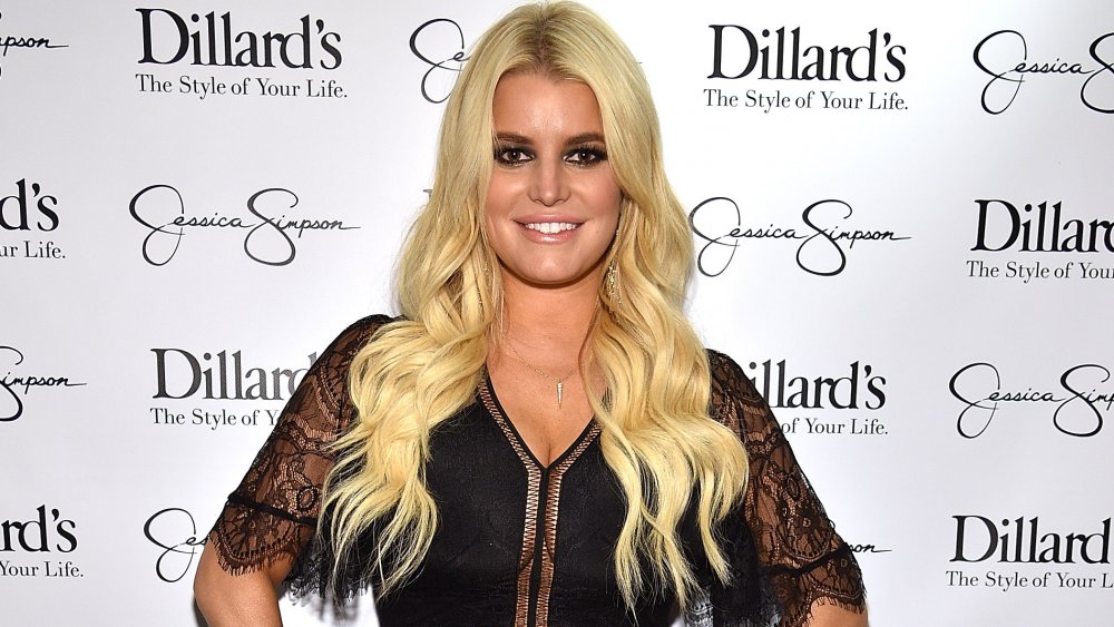 Jessica Simpson en un top de encaje negro, sonriendo con las manos en las caderas