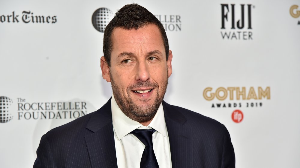 Adam Sandler mirando hacia un lado, sonriendo