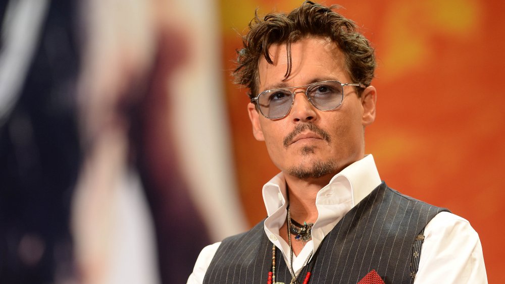 Johnny Depp con camisa blanca, chaleco gris y gafas de sol teñidas de gris