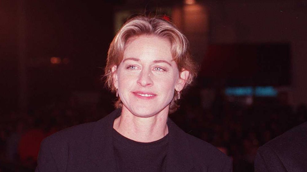 Ellen DeGeneres en un traje negro, posando con una pequeña sonrisa a principios de los 90