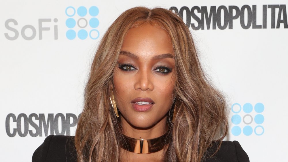 Tyra Banks con un vestido negro, posando en la alfombra roja con una expresión neutra